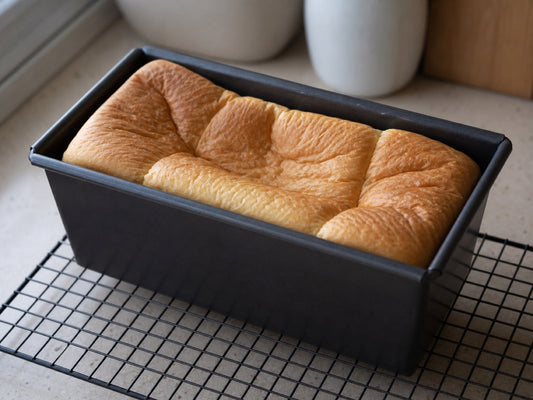 Shokupan loaf with a collapsed wrinkled top in a Pullman loaf pan